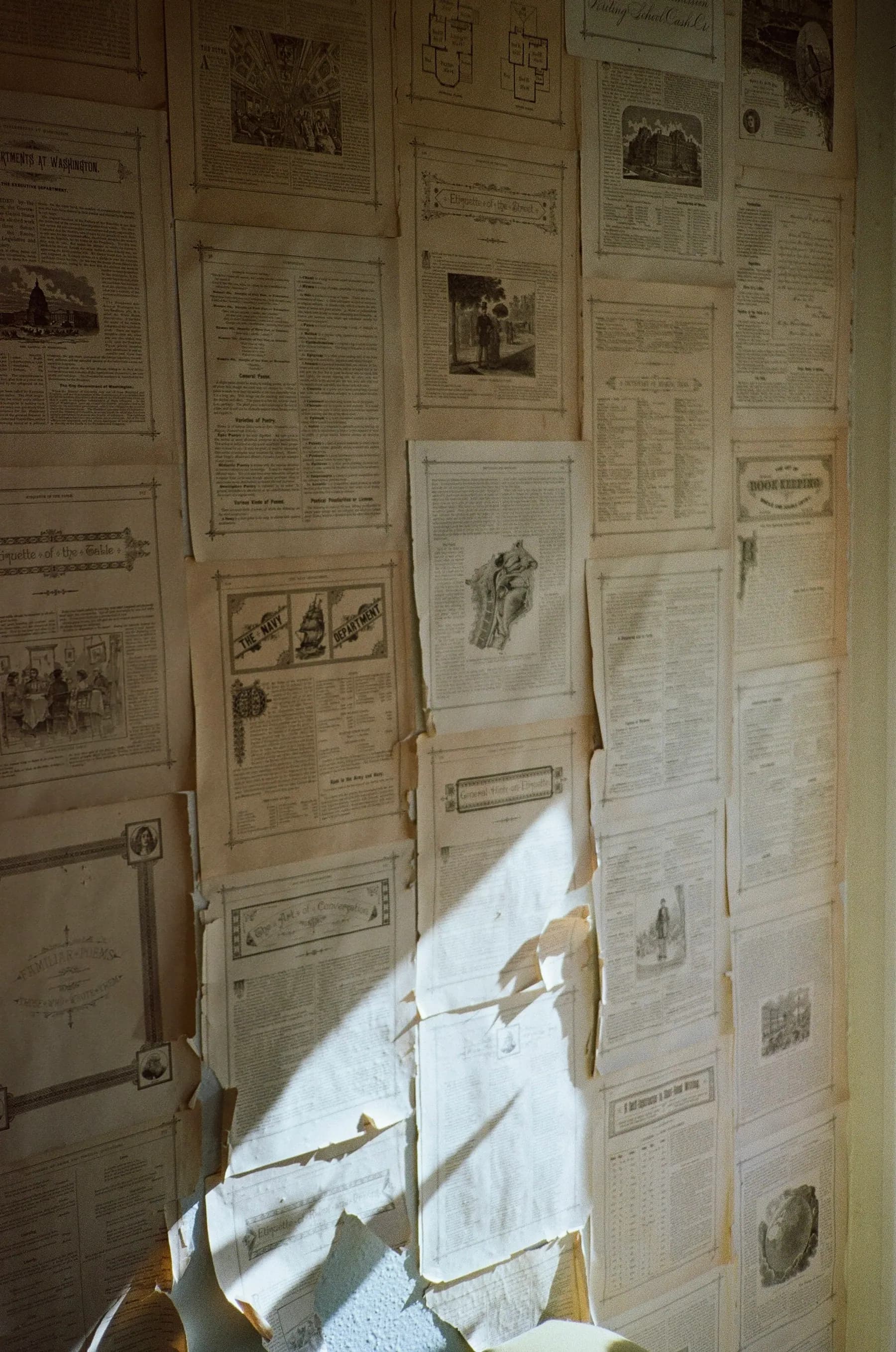 Sunlight falling across a wall layered with old newspaper pages